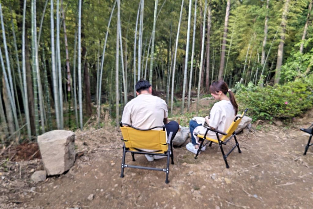 竹林に囲まれた散歩道でキャンプチェアに座りくつろぐ来場者